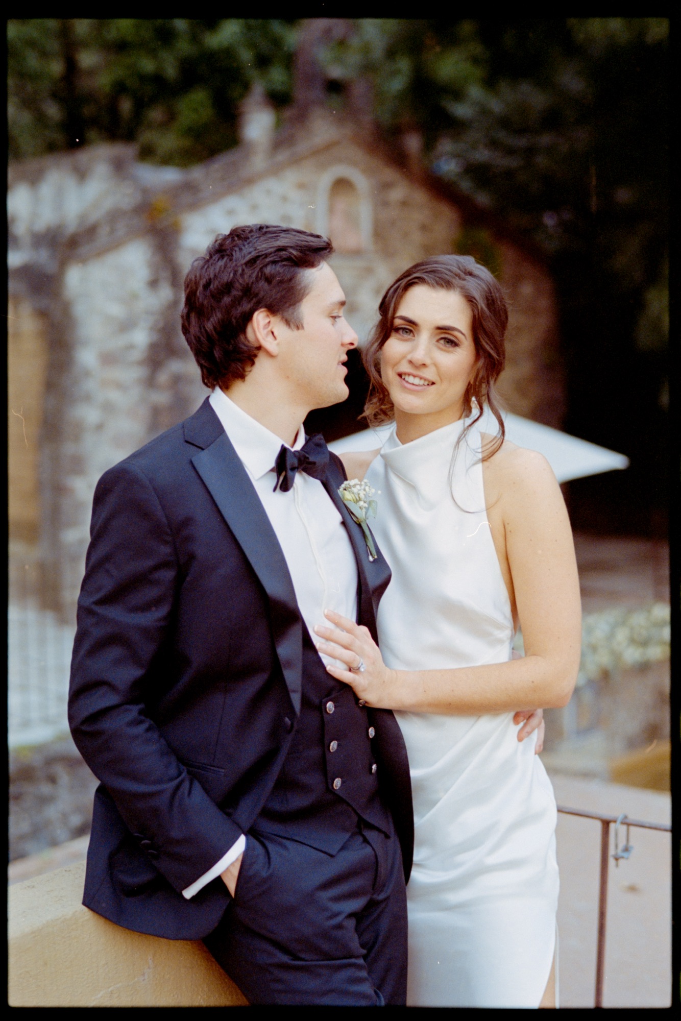 Couple embracing by a stone wall, photographed on film