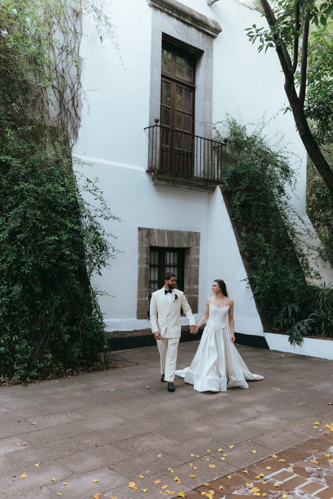 Leyna and Jason walking in a white courtyard in Mexico